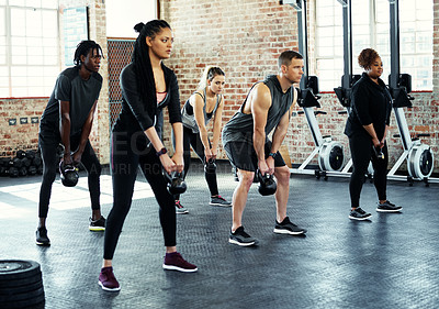 Buy stock photo Shot of a fitness group using dumbbells in their session at the gym