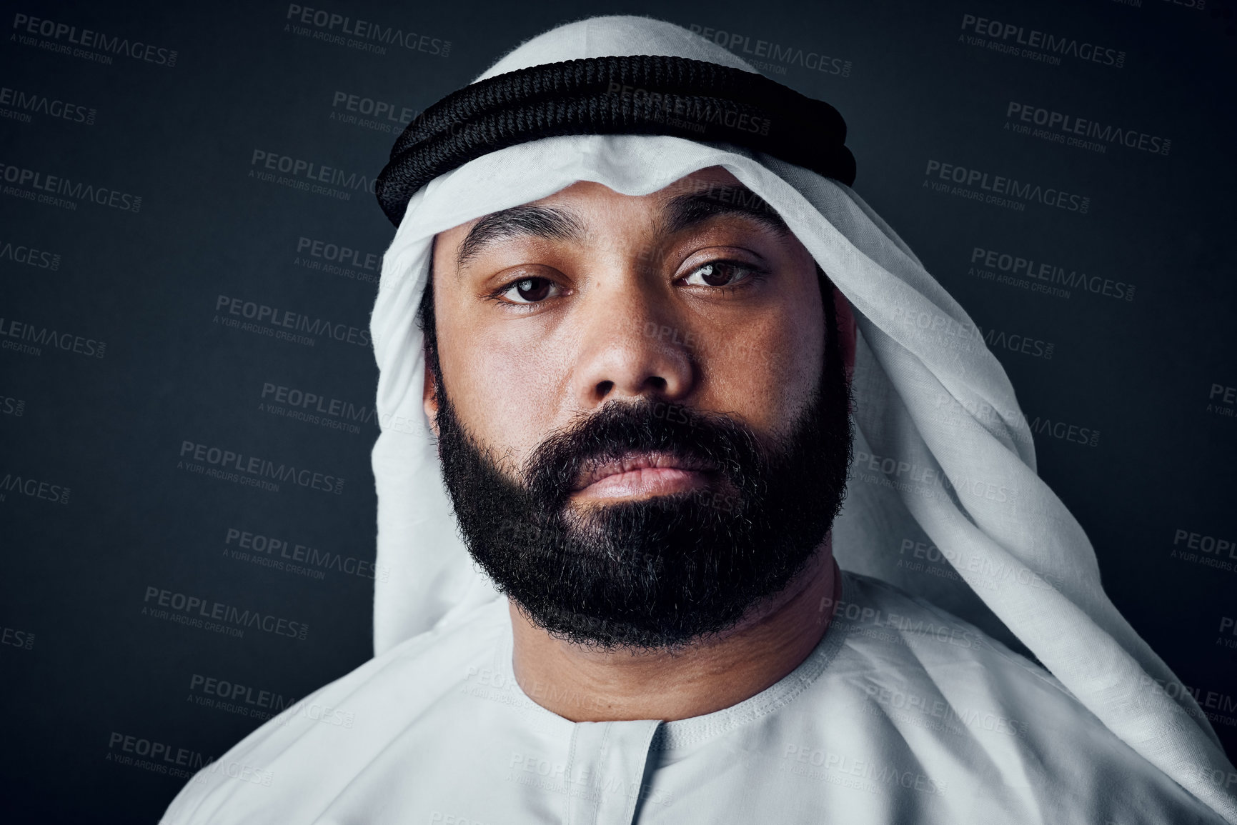 Buy stock photo Studio shot of a young man dressed in Islamic traditional clothing posing against a dark background