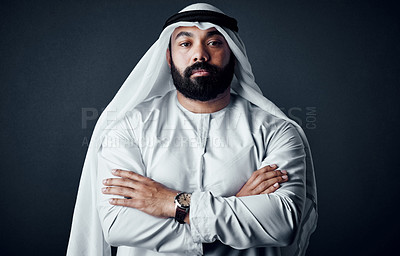 Buy stock photo Studio shot of a young man dressed in Islamic traditional clothing posing against a dark background