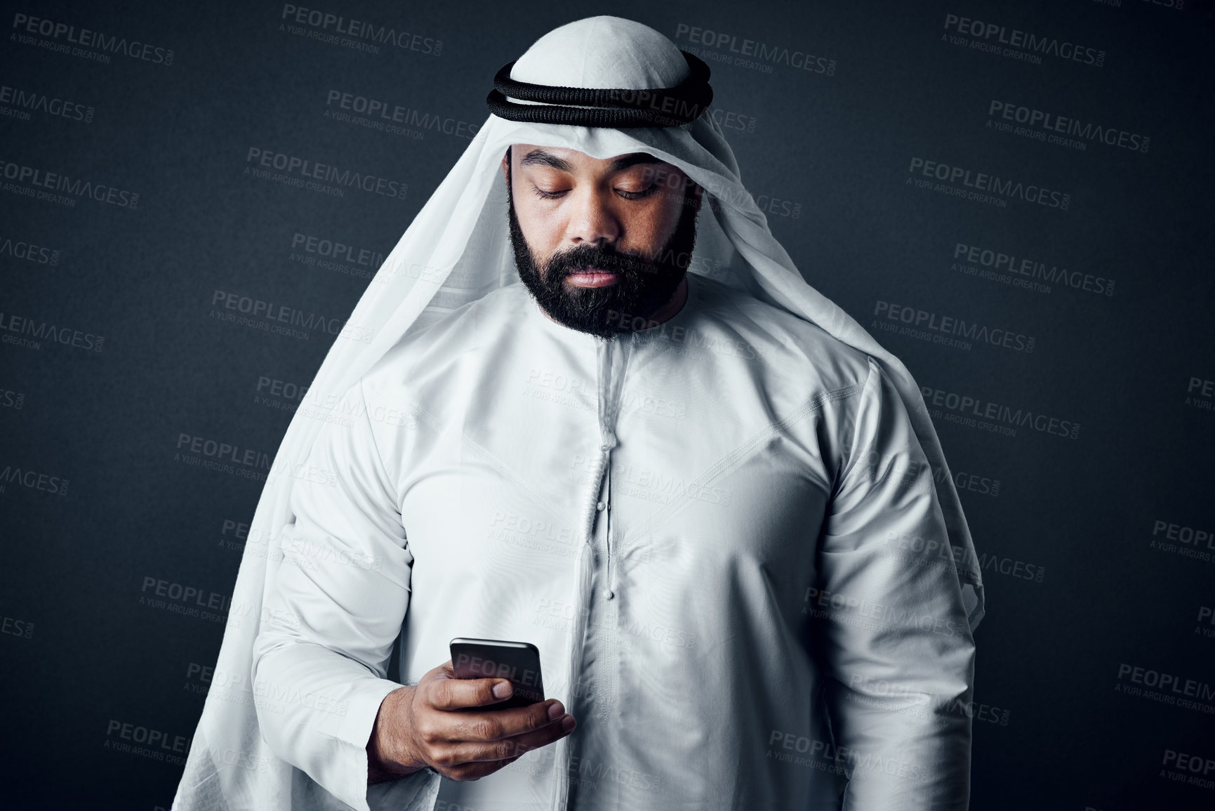 Buy stock photo Studio shot of a young man dressed in Islamic traditional clothing posing against a dark background