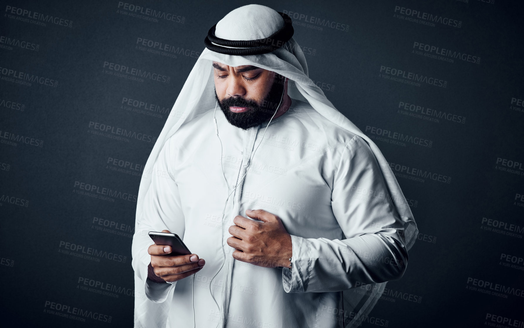 Buy stock photo Studio shot of a young man dressed in Islamic traditional clothing posing against a dark background