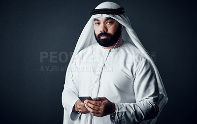 Buy stock photo Studio shot of a young man dressed in Islamic traditional clothing posing against a dark background