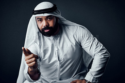 Buy stock photo Studio shot of a young man dressed in Islamic traditional clothing posing against a dark background