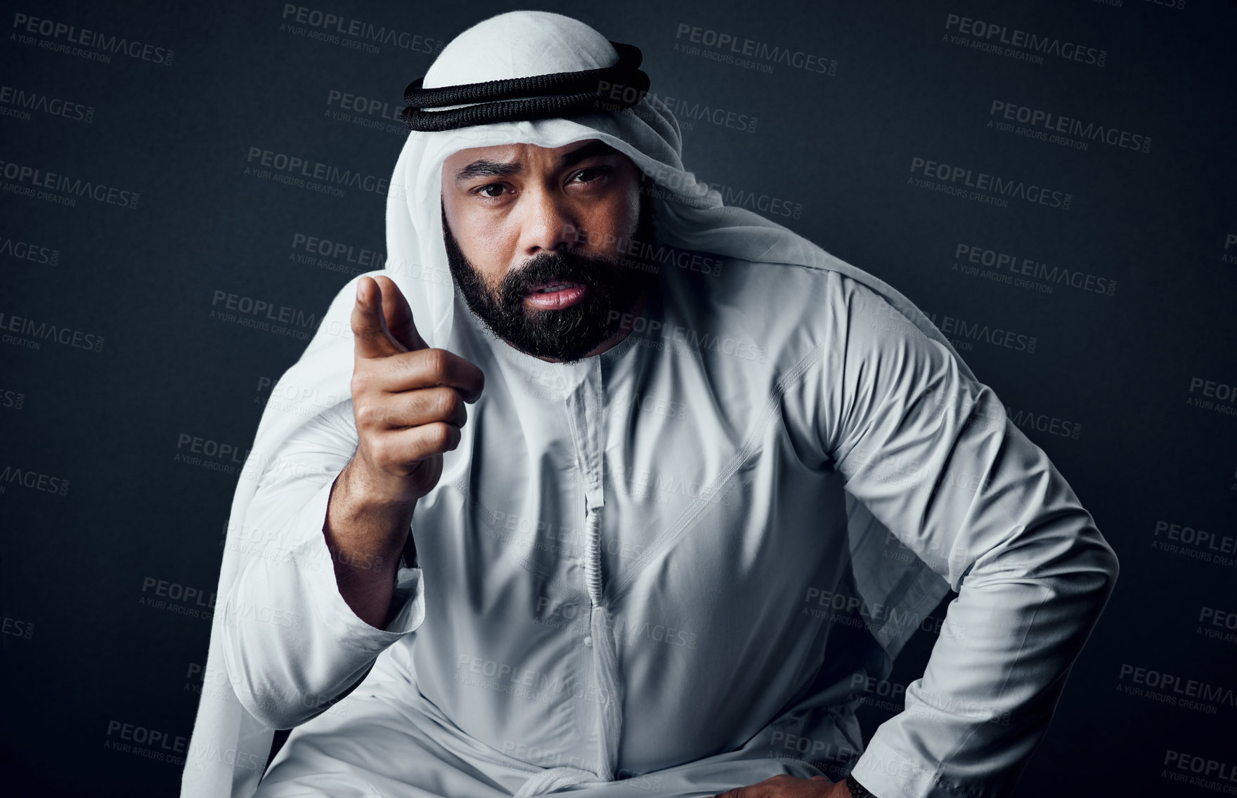 Buy stock photo Studio shot of a young man dressed in Islamic traditional clothing posing against a dark background