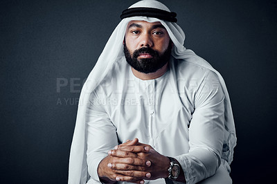 Buy stock photo Studio shot of a young man dressed in Islamic traditional clothing posing against a dark background