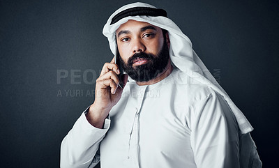 Buy stock photo Studio shot of a young man dressed in Islamic traditional clothing posing against a dark background