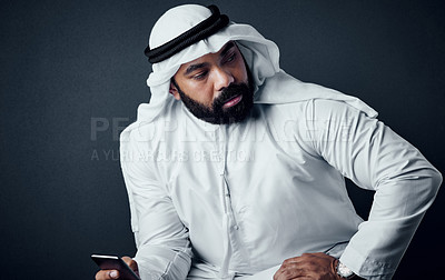 Buy stock photo Studio shot of a young man dressed in Islamic traditional clothing posing against a dark background