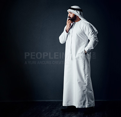 Buy stock photo Studio shot of a young man dressed in Islamic traditional clothing posing against a dark background