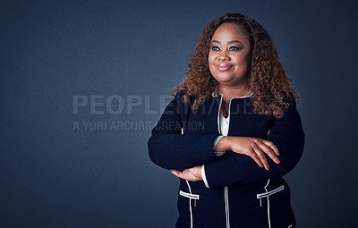 Buy stock photo Studio shot of a cheerful young businesswoman standing with her arms folded while standing against a blue background