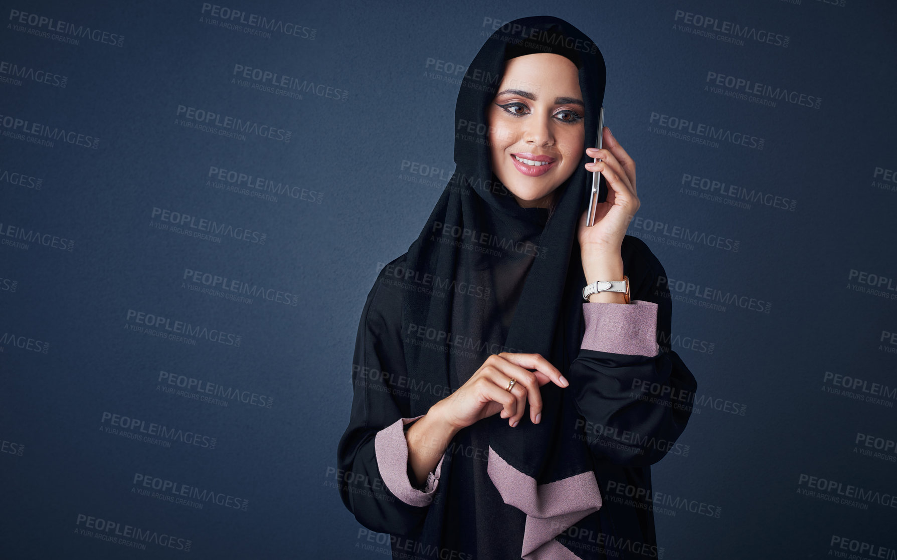 Buy stock photo Studio shot of a young woman wearing a burqa and using a mobile phone against a gray background