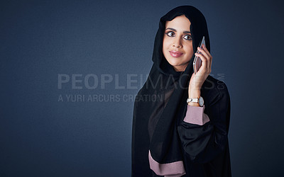 Buy stock photo Studio shot of a young woman wearing a burqa and using a mobile phone against a gray background