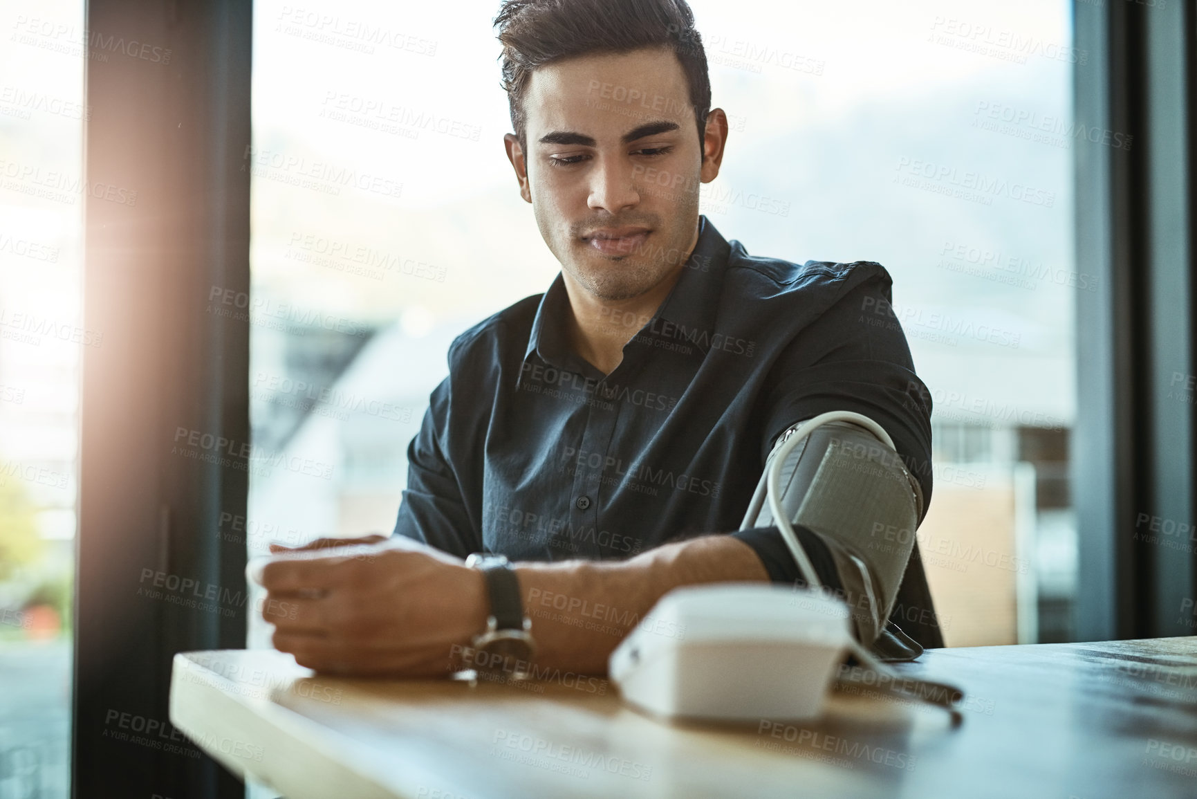 Buy stock photo Shot of a young businessman checking his blood pressure in an office