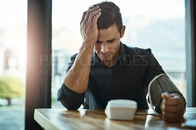 Buy stock photo Shot of a young businessman checking his blood pressure in an office