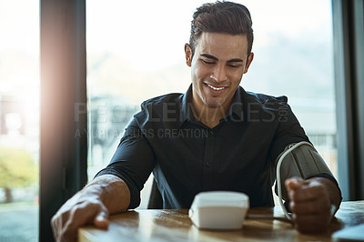 Buy stock photo Shot of a young businessman checking his blood pressure in an office