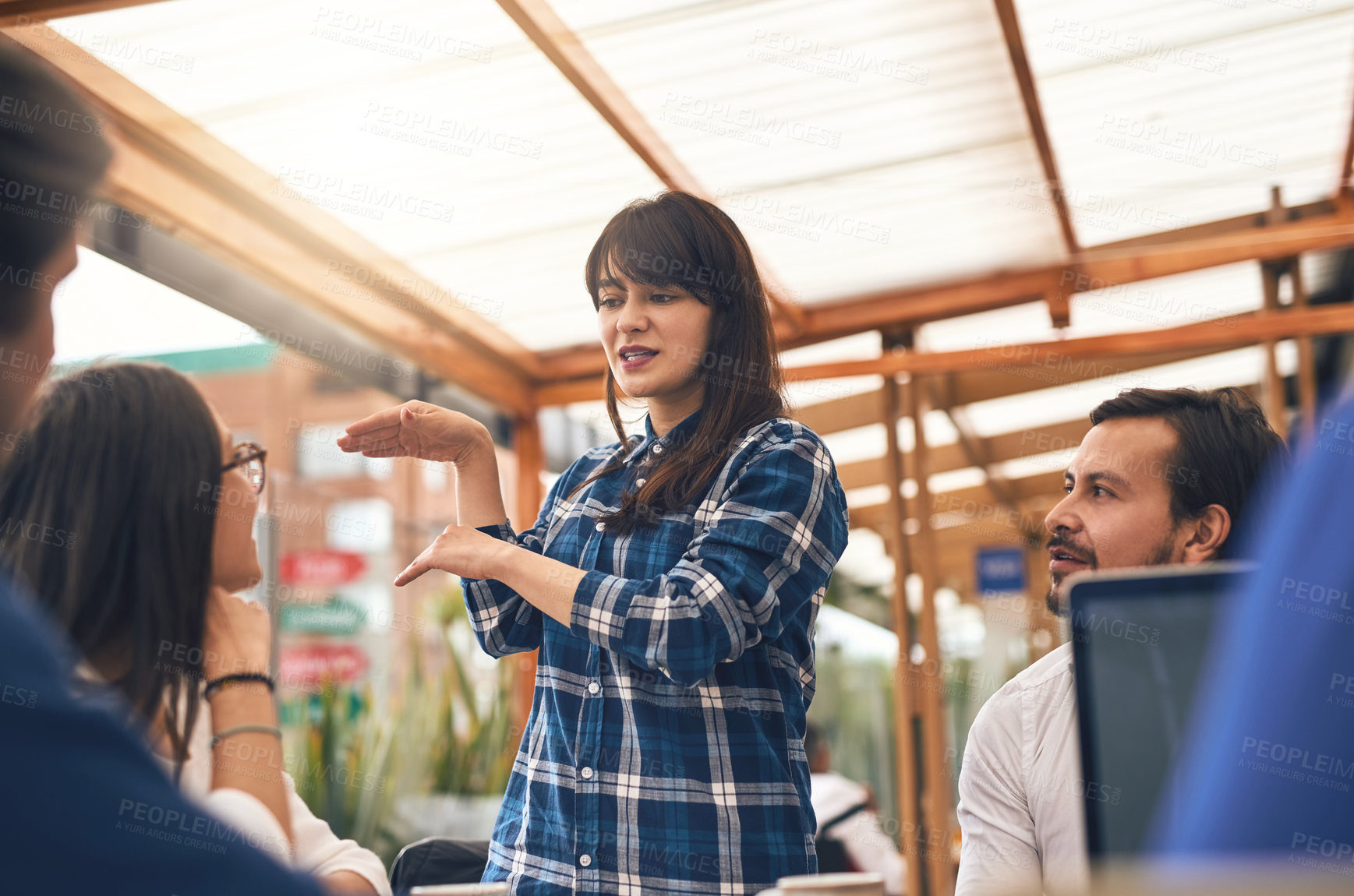 Buy stock photo Shot of a young creative businesswoman explaining to work colleagues about an idea outside of a coffeeshop