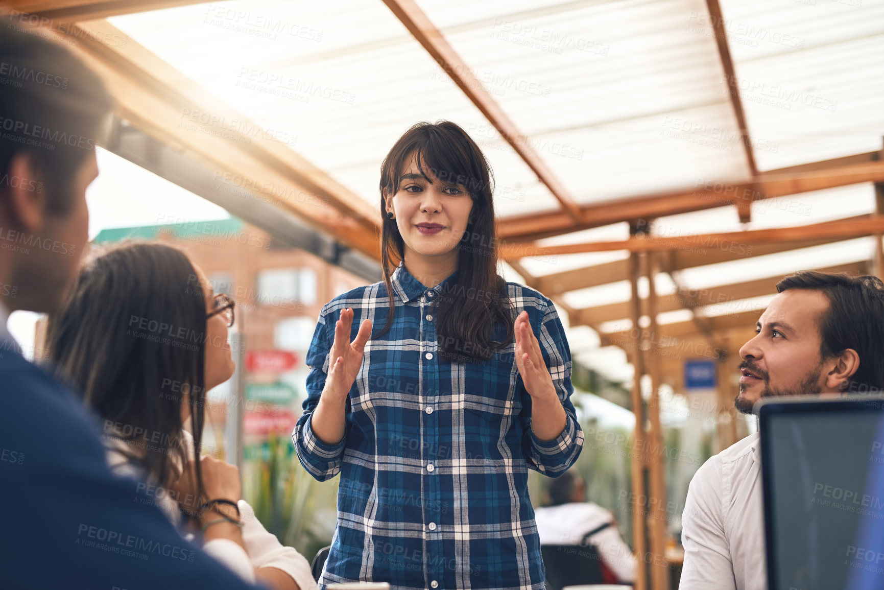 Buy stock photo Shot of a young creative businesswoman explaining to work colleagues about an idea outside of a coffeeshop