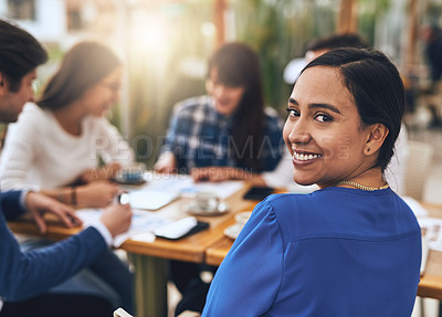 Buy stock photo Portrait of a cheerful young creative businesswoman having a discussion with coworkers at a meeting around a table while looking back at the camera