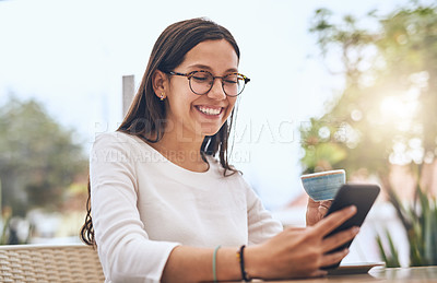 Buy stock photo Shot of a young creative businesswoman using her cellphone while drinking coffee outside a cafe
