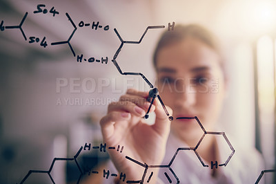 Buy stock photo Shot of a focused young female scientist solving equations on a glass wall in a laboratory
