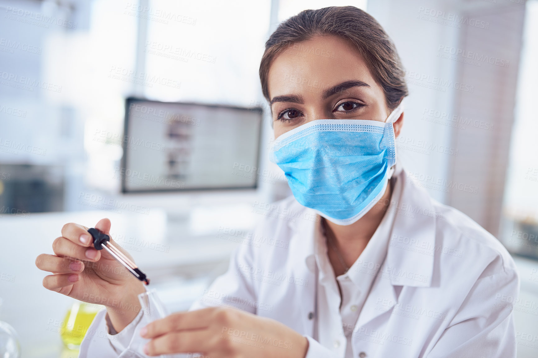 Buy stock photo Portrait of a confident young female scientist wearing a surgical mask while doing a experiment and looking at the camera inside a laboratory