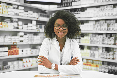 Buy stock photo Portrait of a cheerful young female pharmacist standing with arms folded while looking at the camera in a pharmacy