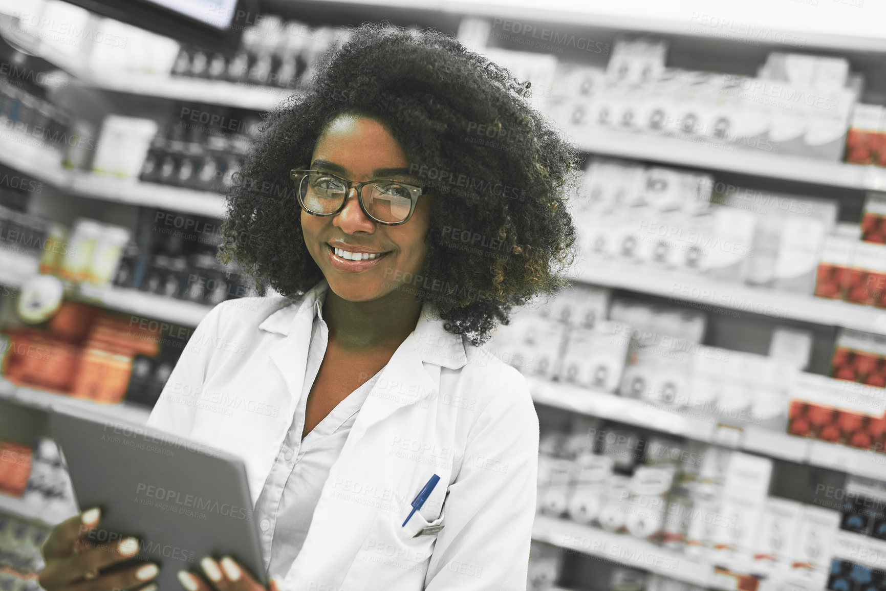 Buy stock photo Portrait of a cheerful young female pharmacist standing with a digital tablet while looking at the camera in a pharmacy