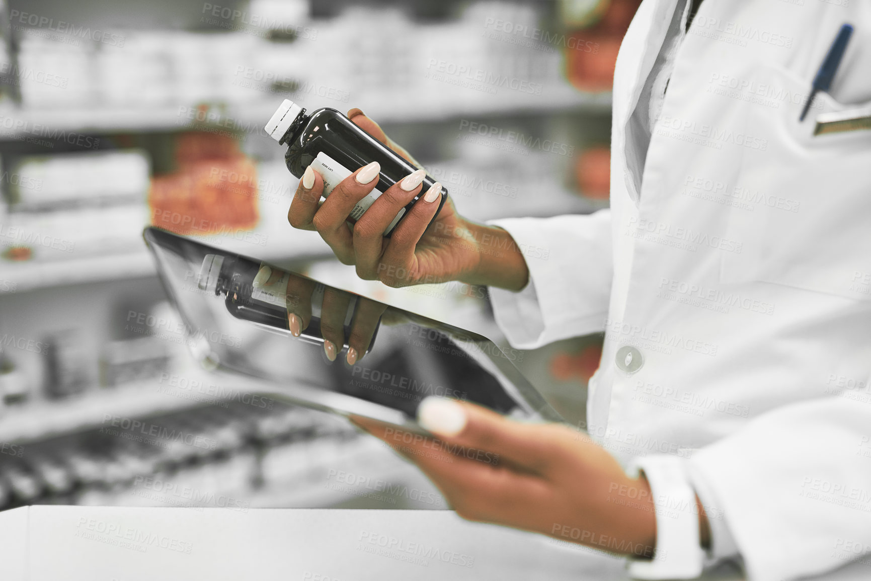 Buy stock photo Shot of a unrecognisable female pharmacist holding a digital tablet in one hand and medication in the other inside of a pharmacy