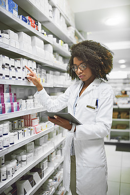 Buy stock photo Shot of a cheerful young female pharmacist checking stock on the shelves of a pharmacy