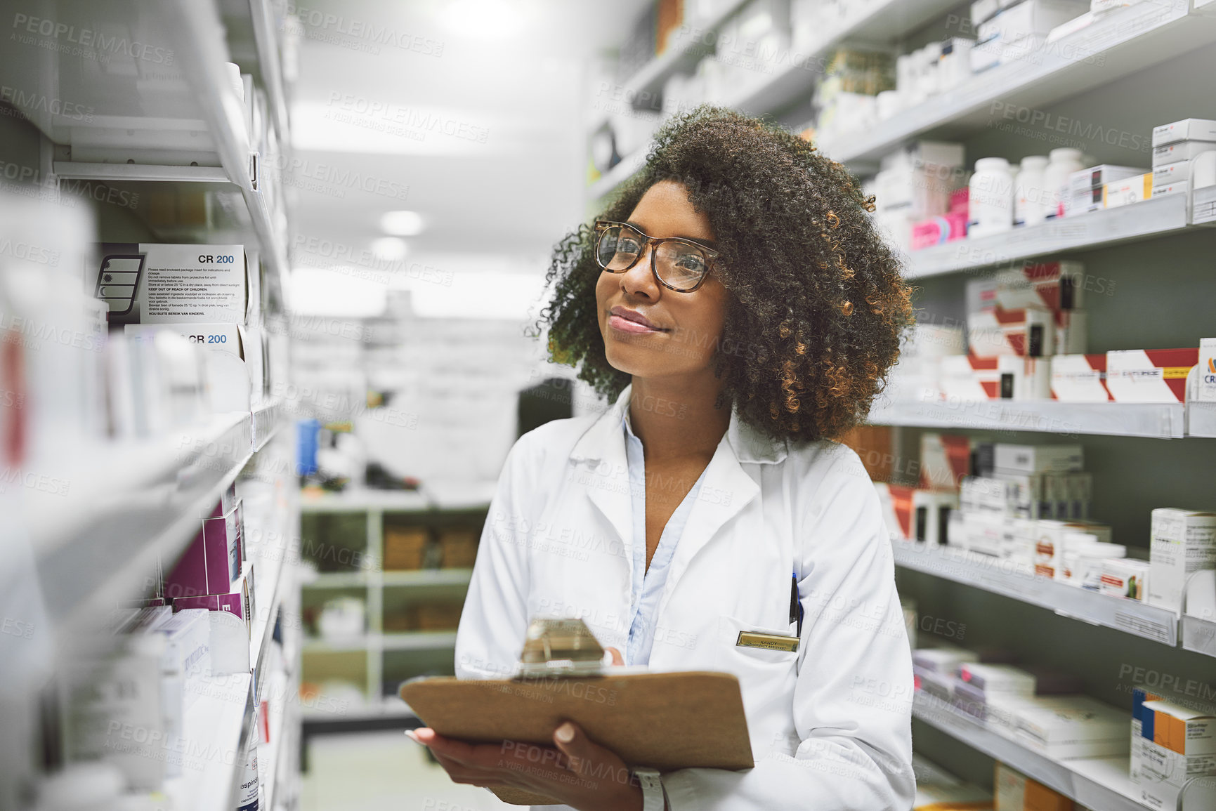 Buy stock photo Shot of a cheerful young female pharmacist checking stock on the shelves of a pharmacy