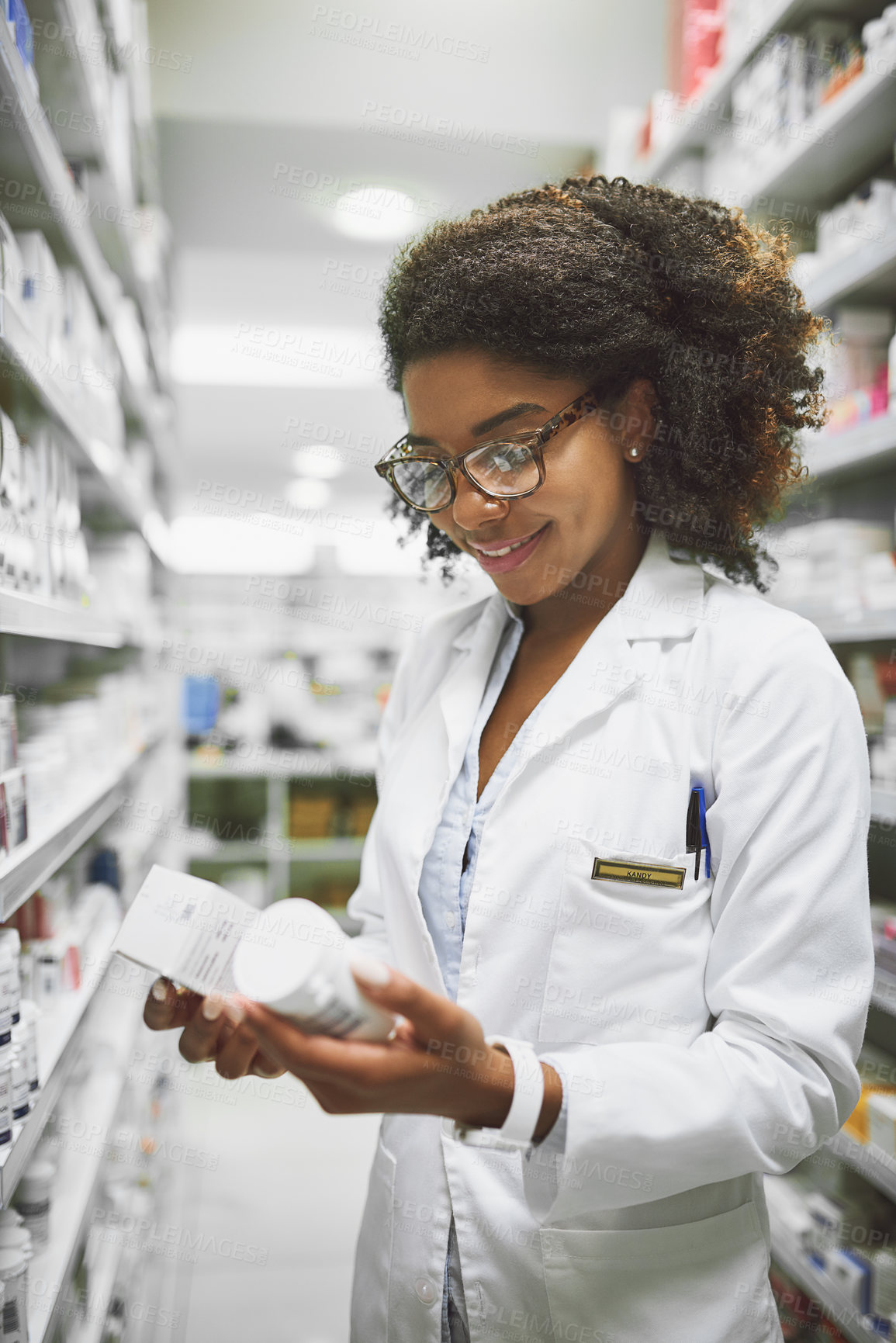 Buy stock photo Shot of a cheerful young female pharmacist holding two different types of medication in each hand in a pharmacy