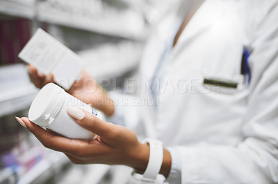 Buy stock photo Shot of a unrecognisable  female pharmacist holding two different types of medication in each hand in a pharmacy
