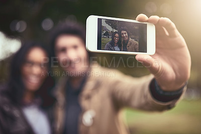 Buy stock photo Shot of a cheerful young couple taking a self portrait together while standing outside in a park