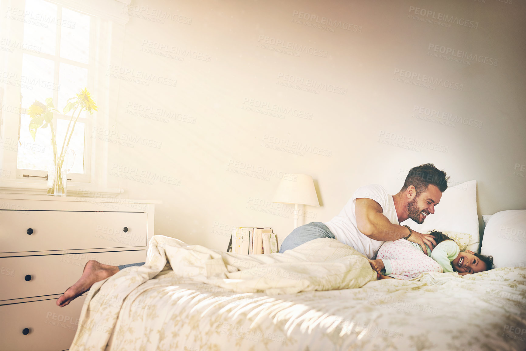 Buy stock photo Shot of a cheerful father and daughter having a tickle fight on the bed at home