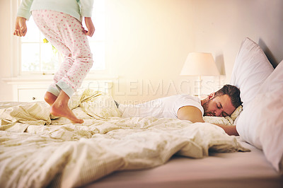 Buy stock photo Shot of a cheerful little girl jumping on the bed to wakeup her sleeping dad at home