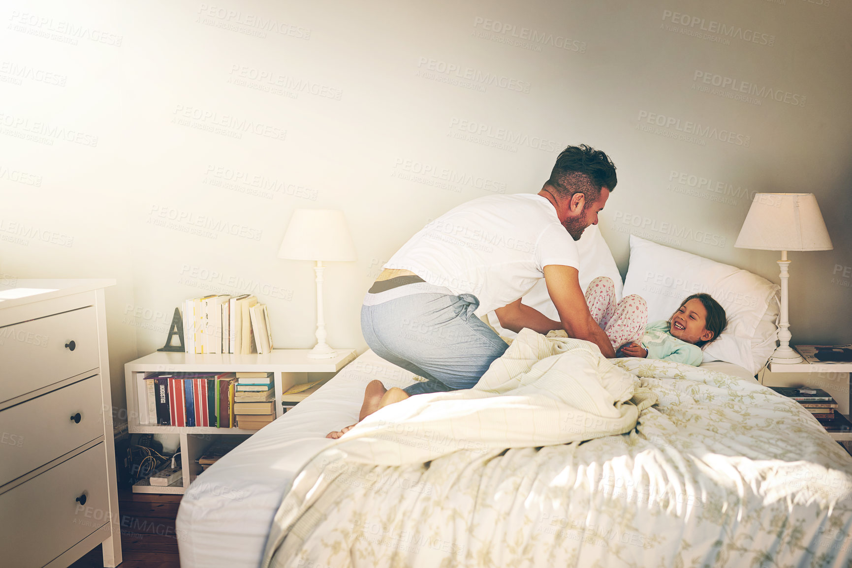 Buy stock photo Shot of a cheerful father and daughter having a tickle fight on the bed at home