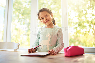 Buy stock photo Portrait of a focused little girl drawing pictures in a book while looking at the camera at home