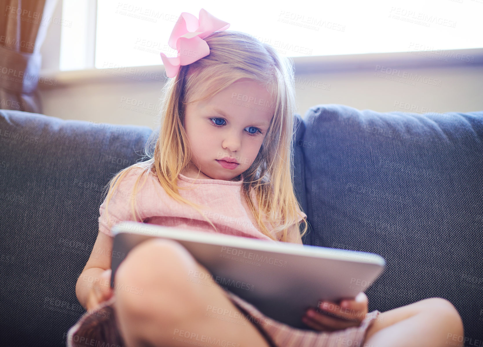 Buy stock photo Shot of an adorable little girl using a digital tablet on the sofa at home