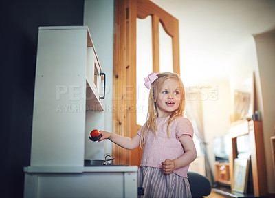 Buy stock photo Shot of an adorable little girl playing with a toy kitchen set at home