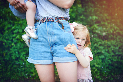 Buy stock photo Shot of a little girl holding onto her mother during a day outdoors