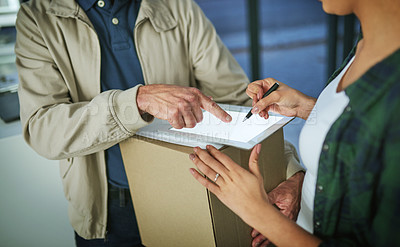 Buy stock photo Cropped shot of a woman using a digital tablet to sign for a package from a delivery man