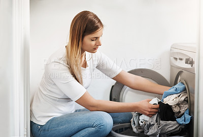 Buy stock photo Shot of an attractive young woman doing laundry at home