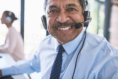 Buy stock photo Portrait of a cheerful businessman talking to a customer using a headset while looking at the camera