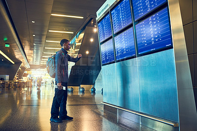 Buy stock photo Shot of a young man looking at a board in an airport