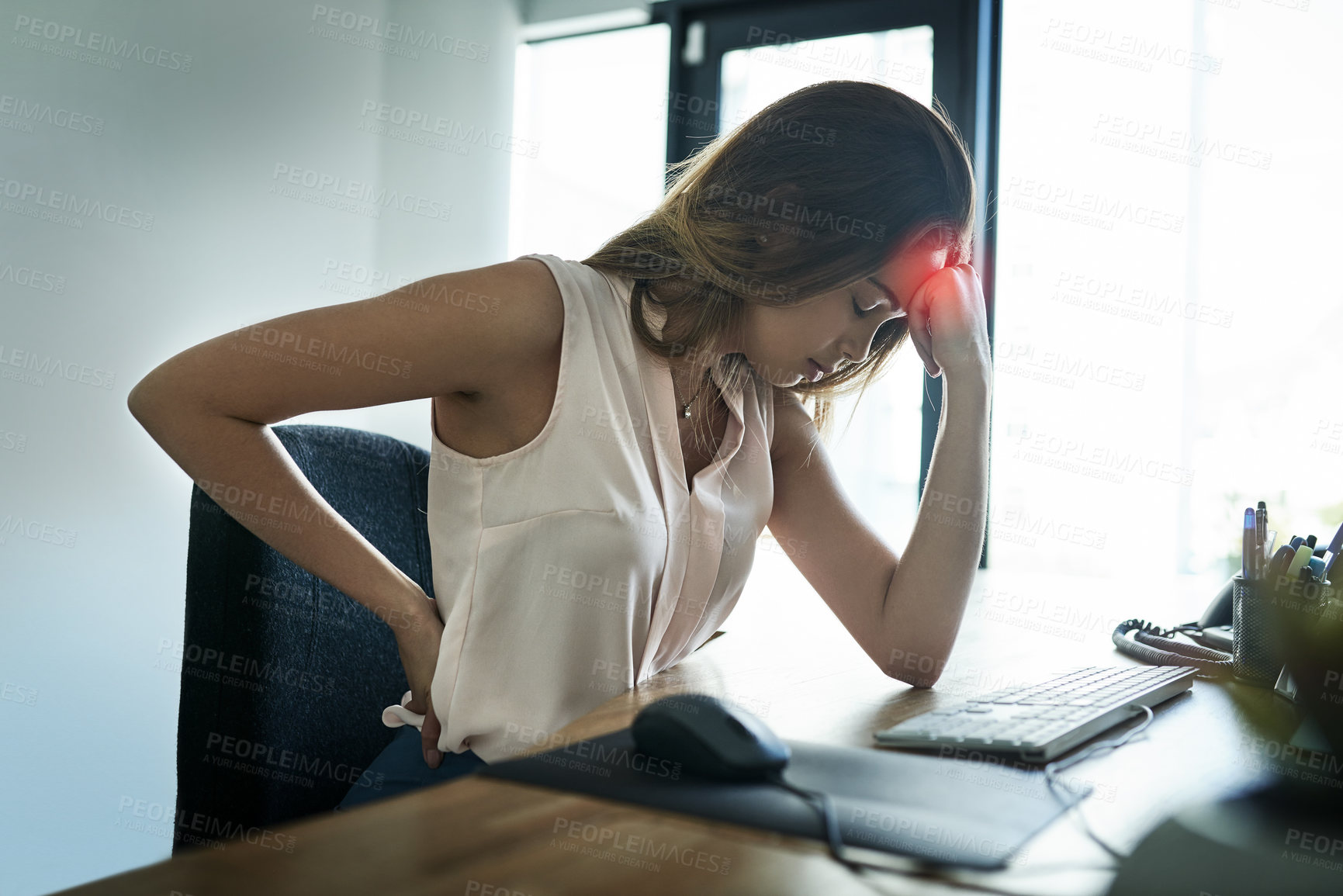 Buy stock photo Shot of a young businesswoman suffering from a headache and back pain while working in an office