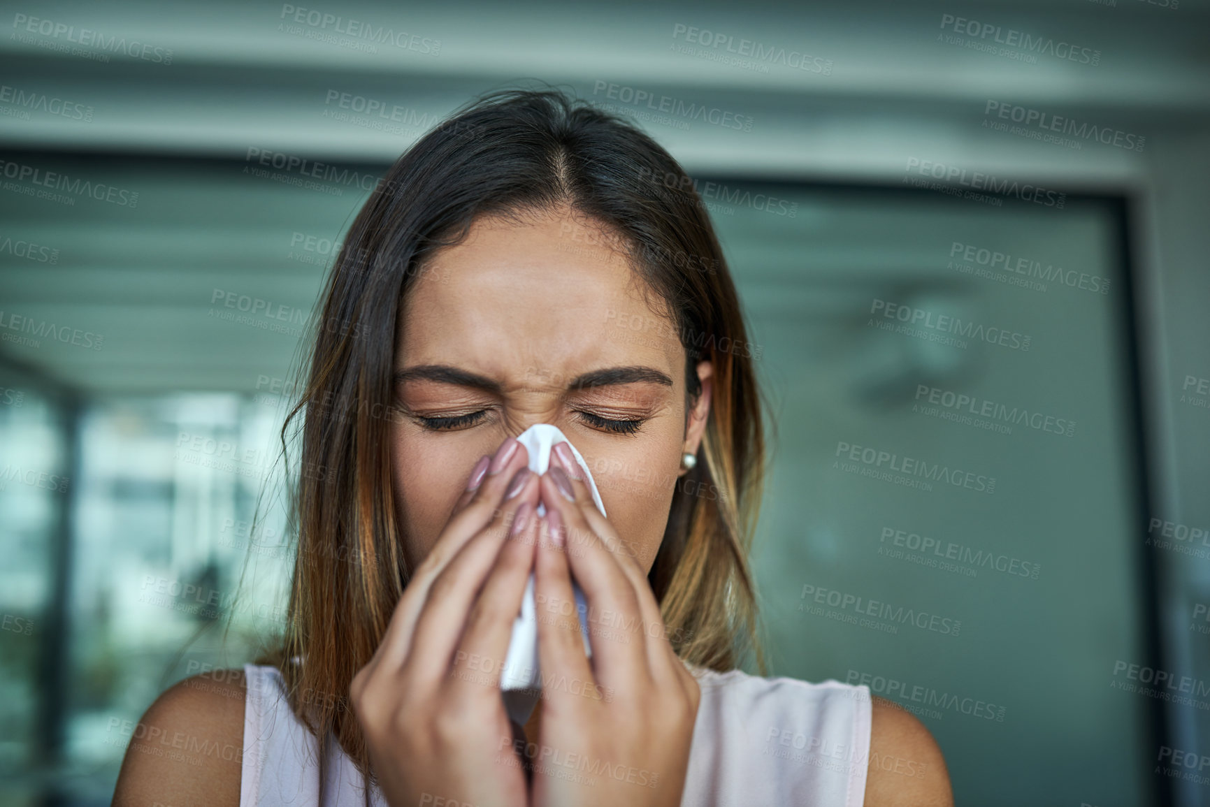 Buy stock photo Shot of a young businesswoman blowing her nose in an office