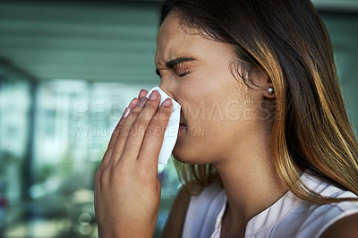 Buy stock photo Shot of a young businesswoman blowing her nose in an office
