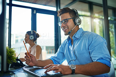 Buy stock photo Shot of a young man working in a team of call center agents