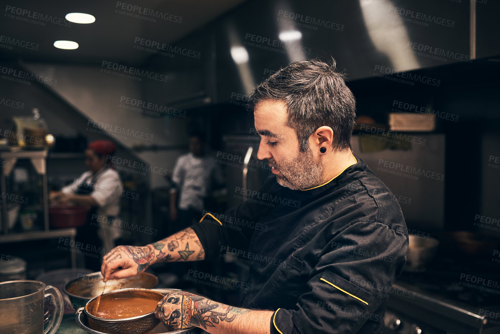 Buy stock photo Shot of a focused chef preparing a dish in the kitchen of a restaurant