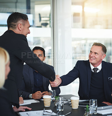 Buy stock photo Shot of two cheerful businessmen shaking hands in agreement in a boardroom at the office