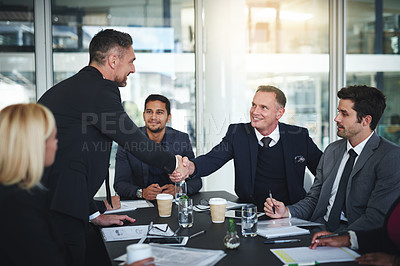 Buy stock photo Shot of two cheerful businessmen shaking hands in agreement in a boardroom at the office